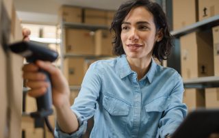 Female Inventory Manager Scans Cardboard Box and with Barcode Scanner