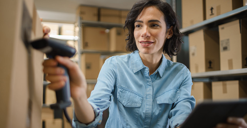 Female Inventory Manager Scans Cardboard Box and with Barcode Scanner inventory management trends