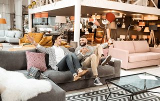 Cheerful laughing couple behaving childishly in furniture showroom