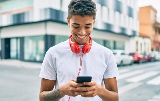 Young latin man smiling happy using smartphone and headphones at the city.